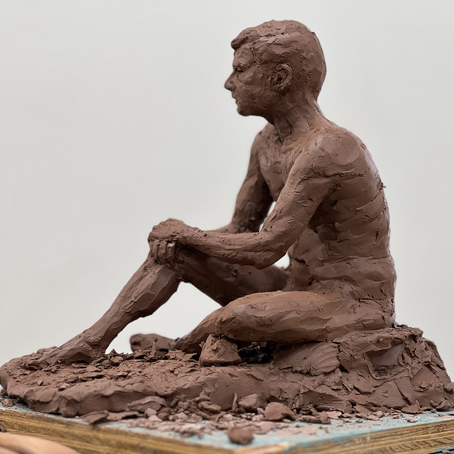 Sculpture of seated man with arms resting on knees